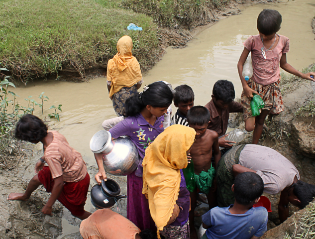 femmes, enfants, hommes Bangladais regroupés autour d'une source d'eau naturelle