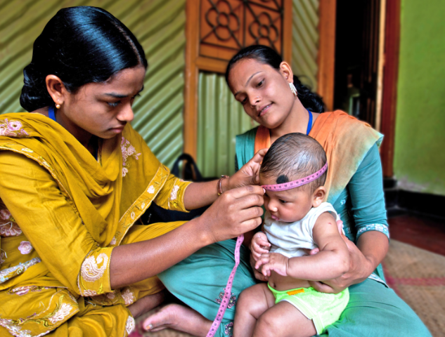femme Bangladaise paramédic qui osculte un bébé tenu dans les bras de sa maman